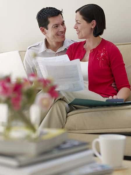 couple smiling over bills stop living paycheck to paycheck