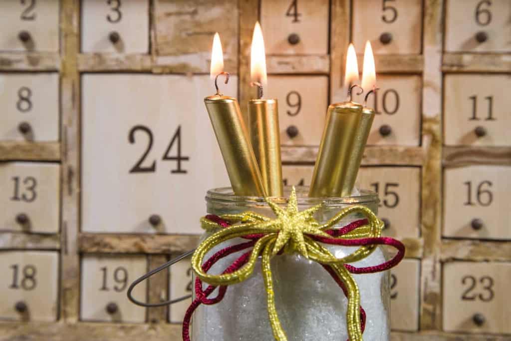 wooden advent calendar with decorative jar and gold candles