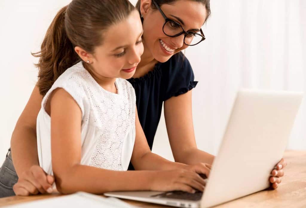 mom homeschooling daughter looking at computer