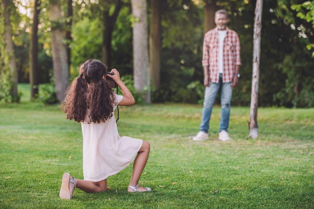 young girl photographing male subject in the woods
