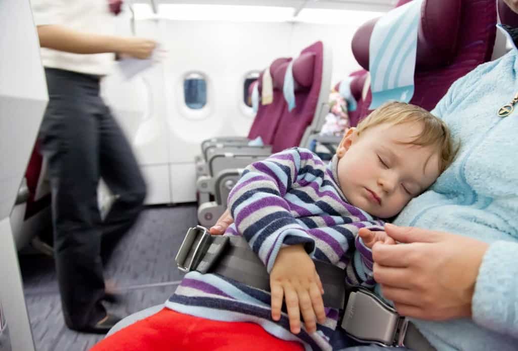 mom on airplane holding sleeping toddler