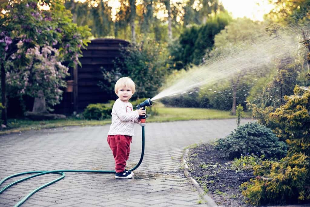 activities for 1-year-olds child holding water hose gardening