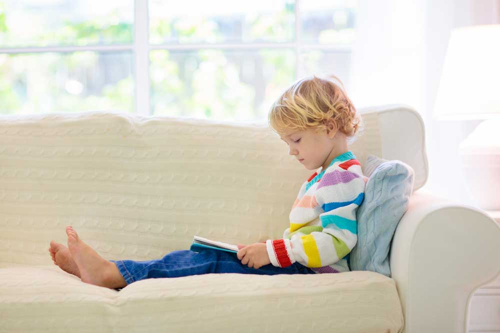 preschool boy reading on sofa