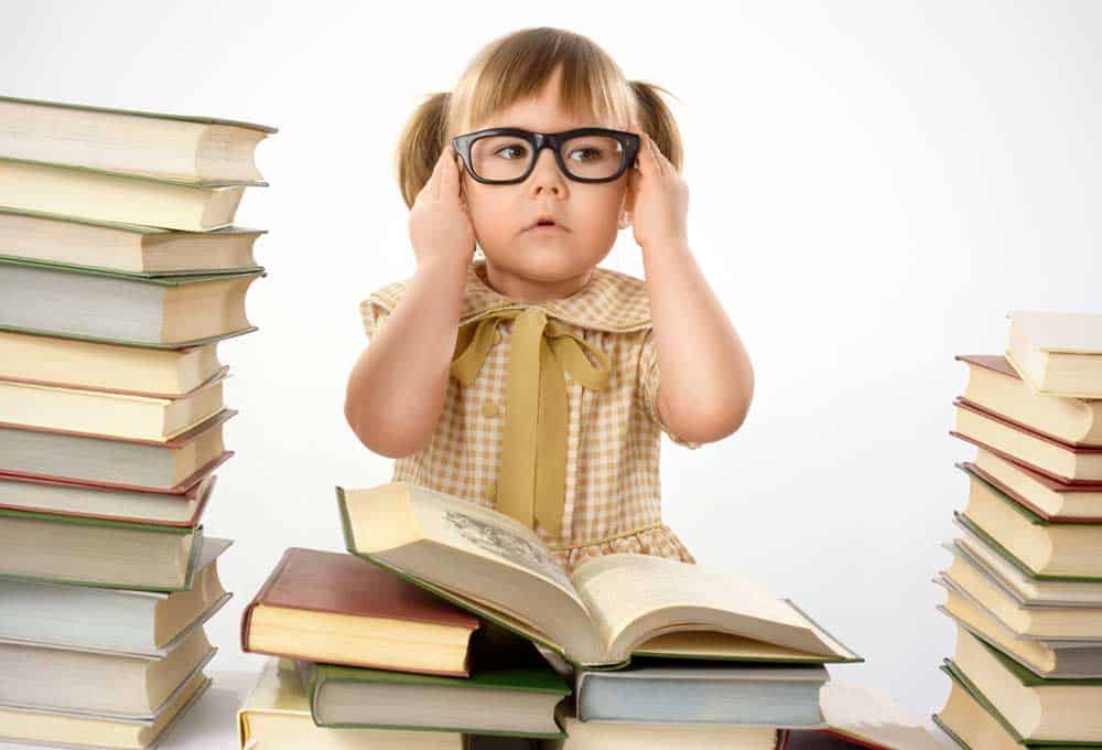 preschooler adjusting glasses surrounded by books