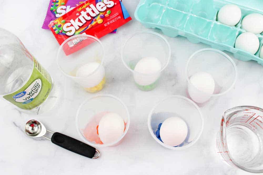 hard-boiled eggs in plastic cups of skittles candy